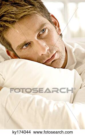 Close-up of a mid adult man hugging a pillow View Large Photo Image Picture - Close-up of a mid adult man hugging a pillow. Fotosearch