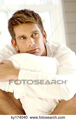 Stock Image - Close-up of a mid adult man hugging a pillow. Fotosearch