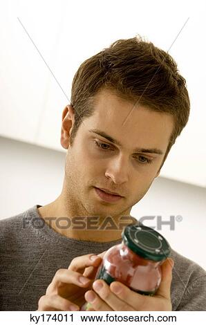 Close-up of a young man reading a label on a jar View Large Photo Image Stock Image - Close-up of a young man reading a label on a jar. Fotosearch