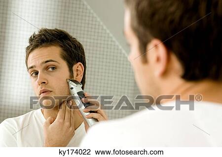 Close-up of a young man shaving with an electric razor View Large Photo Image Stock Image - Close-up of a young man shaving with an electric razor. Fotosearch