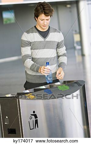 Mid adult man putting an empty bottle into a garbage bin View Large Photo Image Stock Photo - Mid adult man putting an empty bottle into a garbage bin. Fotosearch