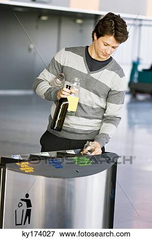 Mid adult man putting empty bottles into a garbage bin View Large Photo Image Stock Photo - Mid adult man putting empty bottles into a garbage bin. Fotosearch