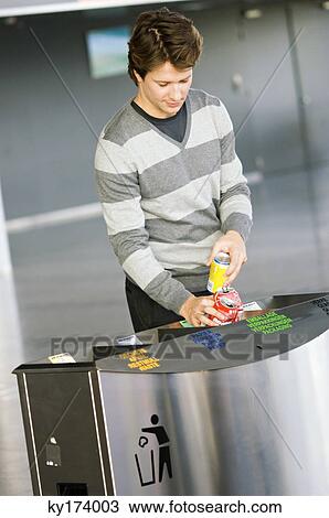 Mid adult man putting empty cans into a garbage bin View Large Photo Image Stock Image - Mid adult man putting empty cans into a garbage bin. Fotosearch