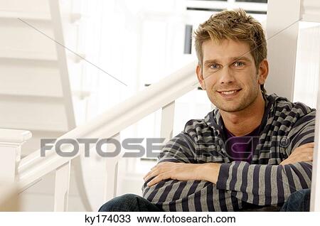 Stock Image - Portrait of a mid adult man sitting in the staircase. Fotosearch