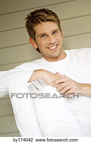 Portrait of a mid adult man sitting on a couch and smiling View Large Photo Image Stock Image - Portrait of a mid adult man sitting on a couch and smiling. Fotosearch