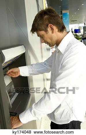 Stock Photo - Side profile of a businessman using an ATM. Fotosearch