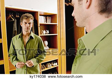 Side profile of a mid adult man getting dressed View Large Photo Image Stock Photo - Side profile of a mid adult man getting dressed. Fotosearch