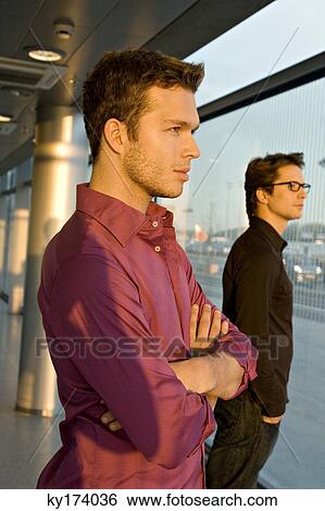 Side profile of two businessmen standing together View Large Photo Image Stock Photograph - Side profile of two businessmen standing together. Fotosearch