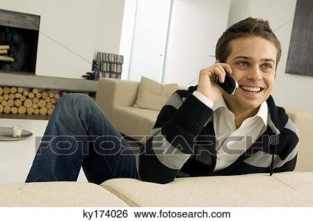 Young man talking on a mobile phone and smiling View Large Photo Image Stock Photograph - Young man talking on a mobile phone and smiling. Fotosearch
