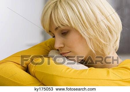 Close-up of a young woman hugging a cushion and thinking View Large Photo Image Stock Image - Close-up of a young woman hugging a cushion and thinking. Fotosearch