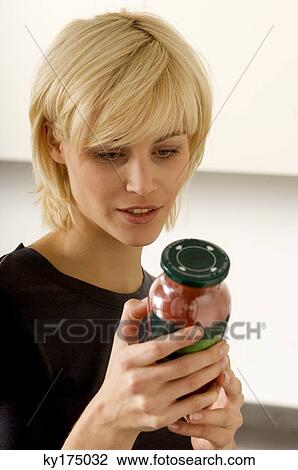 Close-up of a young woman reading a label on a jar View Large Photo Image Stock Image - Close-up of a young woman reading a label on a jar. Fotosearch