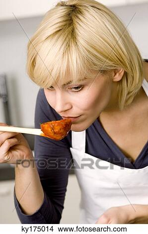 Picture - Close-up of a young woman smelling tomato sauce. Fotosearch