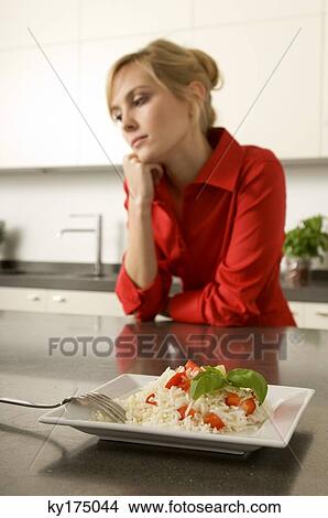 Plate of rice in front of a young woman leaning against a kitchen counter View Large Photo Image Picture - Plate of rice in front of a young woman leaning against a kitchen counter. Fotosearch