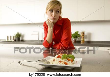 Plate of rice in front of a young woman leaning against a kitchen counter View Large Photo Image Stock Photo - Plate of rice in front of a young woman leaning against a kitchen counter. Fotosearch