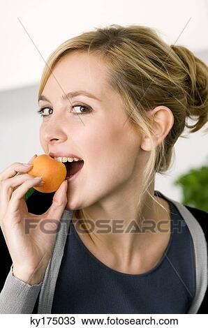 Portrait of a young woman eating an apricot View Large Photo Image Stock Image - Portrait of a young woman eating an apricot. Fotosearch