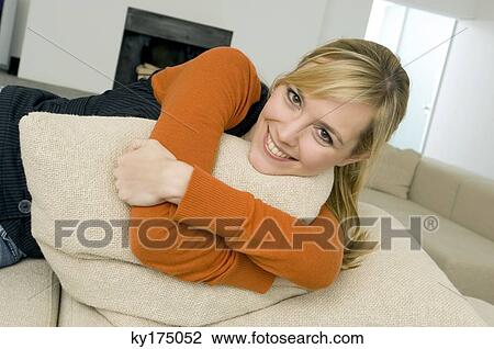 Portrait of a young woman hugging a cushion and smiling View Large Photo Image Stock Image - Portrait of a young woman hugging a cushion and smiling. Fotosearch