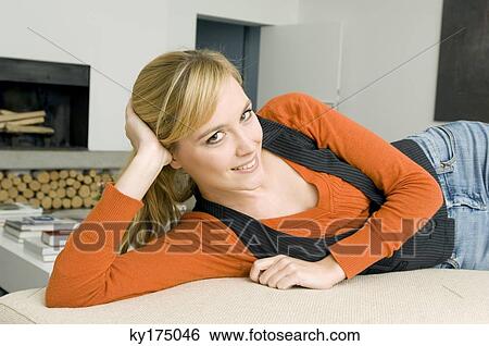 Portrait of a young woman lying on a couch and smiling View Large Photo Image Stock Photograph - Portrait of a young woman lying on a couch and smiling. Fotosearch