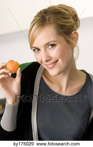 Portrait of a young woman showing an apricot View Large Photo Image Stock Photo - Portrait of a young woman showing an apricot. Fotosearch