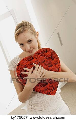 Young woman hugging a heart shape gift and smiling View Large Photo Image Stock Photo - Young woman hugging a heart shape gift and smiling. Fotosearch