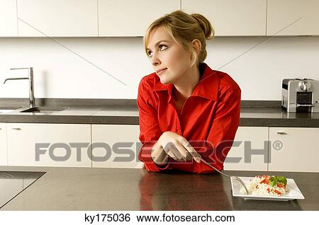 Young woman leaning against a kitchen counter and thinking View Large Photo Image Stock Photograph - Young woman leaning against a kitchen counter and thinking. Fotosearch