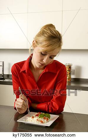 Young woman leaning against a kitchen counter and holding a fork View Large Photo Image Stock Photography - Young woman leaning against a kitchen counter and holding a fork. Fotosearch