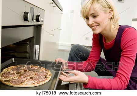 Young woman putting a tray of pizza into an oven View Large Photo Image Stock Photo - Young woman putting a tray of pizza into an oven. Fotosearch