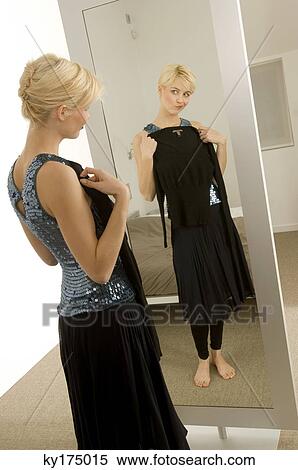 Stock Photography - Young woman trying on a dress in front of a mirror. Fotosearch