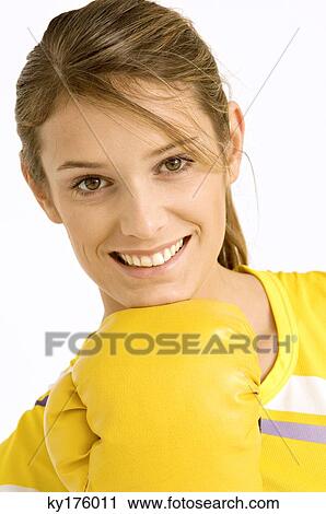 Stock Image - Portrait of a female boxer wearing a boxing glove and smiling. Fotosearch