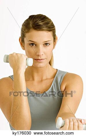 Portrait of a young woman exercising with dumbbells View Large Photo Image Stock Image - Portrait of a young woman exercising with dumbbells. Fotosearch