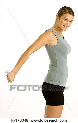 Portrait of a young woman exercising with a dumbbell View Large Photo Image Stock Photo - Portrait of a young woman exercising with a dumbbell. Fotosearch