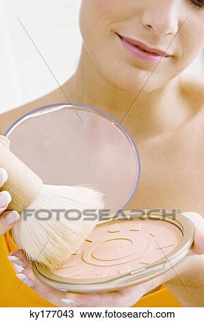Close-up of a young woman applying make-up View Large Photo Image Stock Image - Close-up of a young woman applying make-up. Fotosearch