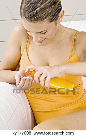 Close-up of a young woman squeezing moisturizer from a bottle View Large Photo Image Stock Photo - Close-up of a young woman squeezing moisturizer from a bottle. Fotosearch
