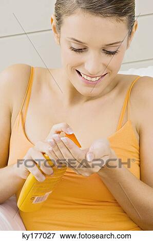 Close-up of a young woman squeezing moisturizer from a bottle View Large Photo Image Stock Photo - Close-up of a young woman squeezing moisturizer from a bottle. Fotosearch