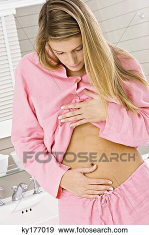 Close-up of a young woman touching her abdomen View Large Photo Image Stock Photo - Close-up of a young woman touching her abdomen. Fotosearch
