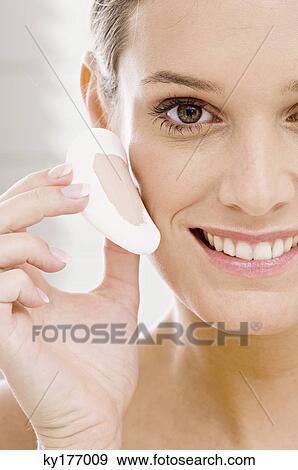 Portrait of a young woman applying face powder View Large Photo Image Stock Photo - Portrait of a young woman applying face powder. Fotosearch