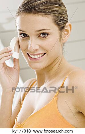 Portrait of a young woman applying face powder View Large Photo Image Stock Photo - Portrait of a young woman applying face powder. Fotosearch