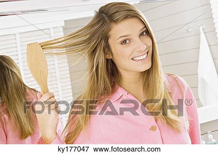 Portrait of a young woman brushing her hair View Large Photo Image Stock Photo - Portrait of a young woman brushing her hair. Fotosearch