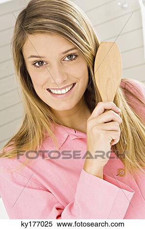 Portrait of a young woman brushing her hair View Large Photo Image Stock Photography - Portrait of a young woman brushing her hair. Fotosearch