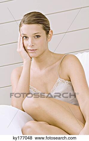 Portrait of a young woman sitting in an armchair View Large Photo Image Stock Photo - Portrait of a young woman sitting in an armchair. Fotosearch