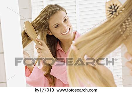 Reflection of a young woman brushing her hair View Large Photo Image Stock Image - Reflection of a young woman brushing her hair. Fotosearch