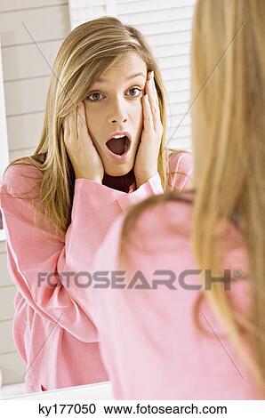 Reflection of a young woman shocked and looking in mirror View Large Photo Image Stock Image - Reflection of a young woman shocked and looking in mirror. Fotosearch