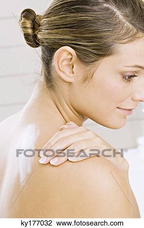 Side profile of a young woman applying moisturizer on her shoulder View Large Photo Image Stock Image - Side profile of a young woman applying moisturizer on her shoulder. Fotosearch