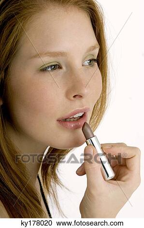Close-up of a young woman applying lipstick View Large Photo Image Stock Image - Close-up of a young woman applying lipstick. Fotosearch