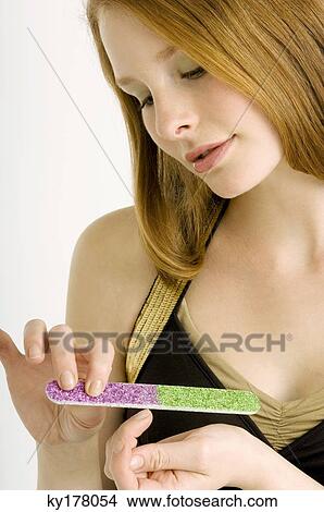 Close-up of a young woman filing her nails View Large Photo Image Picture - Close-up of a young woman filing her nails. Fotosearch