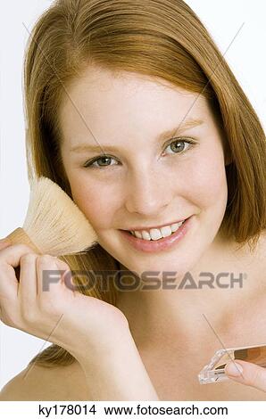 Portrait of a young woman applying blush on her cheek View Large Photo Image Picture - Portrait of a young woman applying blush on her cheek. Fotosearch