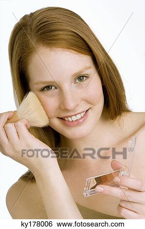 Portrait of a young woman applying blush on her cheek View Large Photo Image Stock Photograph - Portrait of a young woman applying blush on her cheek. Fotosearch