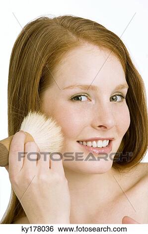 Portrait of a young woman applying blush on her cheek View Large Photo Image Stock Photograph - Portrait of a young woman applying blush on her cheek. Fotosearch