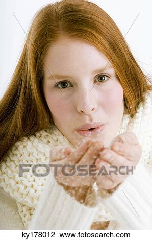 Stock Image - Portrait of a young woman blowing snow from her cupped hands. Fotosearch