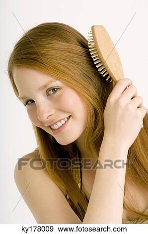 Portrait of a young woman brushing her hair and smiling View Large Photo Image Stock Photo - Portrait of a young woman brushing her hair and smiling. Fotosearch