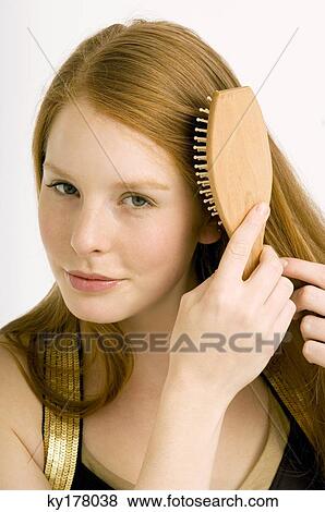 Portrait of a young woman brushing her hair View Large Photo Image Stock Photo - Portrait of a young woman brushing her hair. Fotosearch